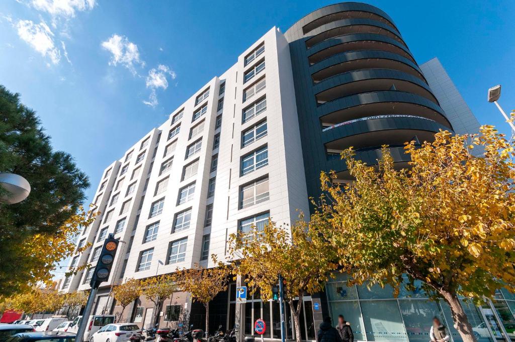 ein Gebäude in einer Stadtstraße mit Menschen davor in der Unterkunft Palm Suites Gran Vía in Alicante