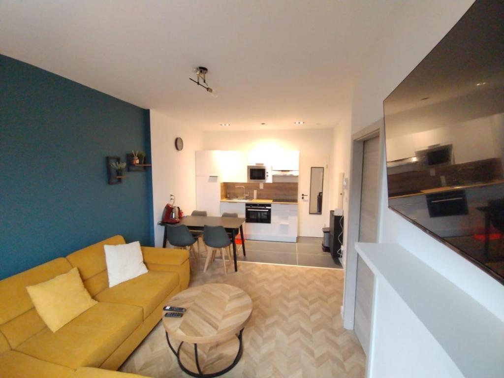 a living room with a yellow couch and a table at Appartement spacieux in Lille