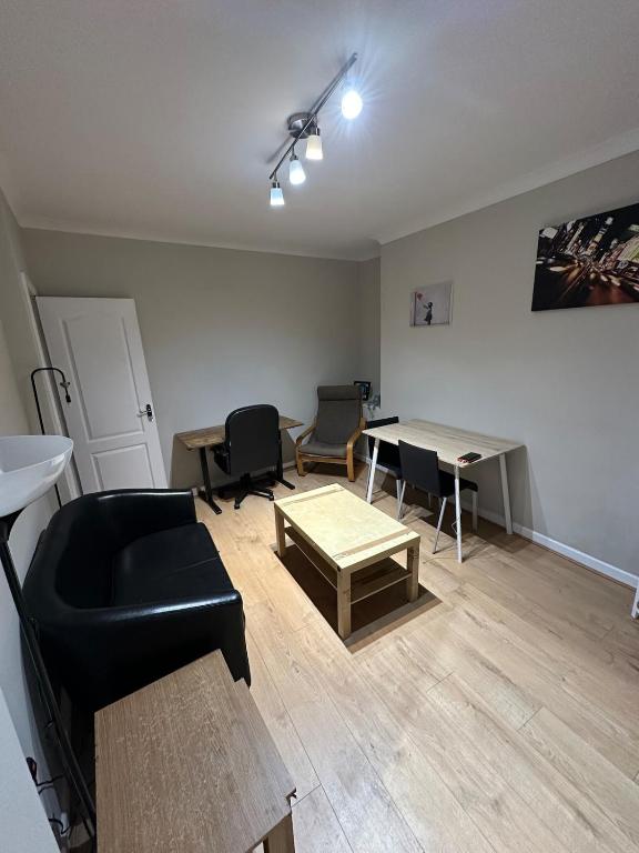 Una sala de estar con un sofá negro y una mesa. en Workers & Families Home- Close to Transport & Town, en Porth