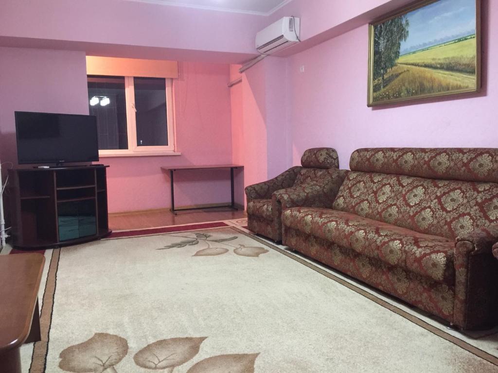 sala de estar con sofá y TV en Bishkek Apartment Central, en Bishkek