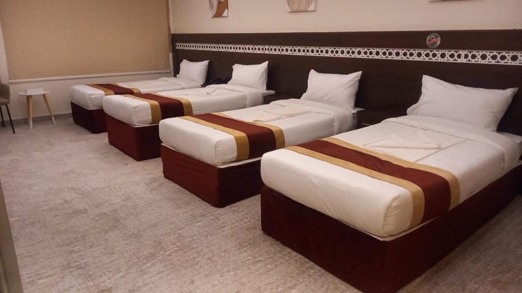 una fila di 4 posti letto in una camera d'albergo di فندق اصيلة الاندلس a Muzdalifah