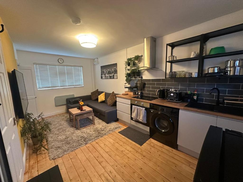 eine Küche und ein Wohnzimmer mit Sofa und Tisch in der Unterkunft 1a Woodlands Edge in Trowbridge