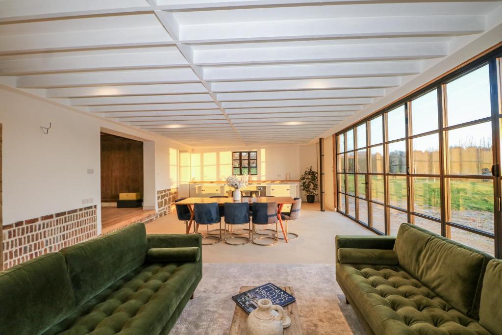 a living room with green furniture and large windows at Great Noven Farm in Lewes