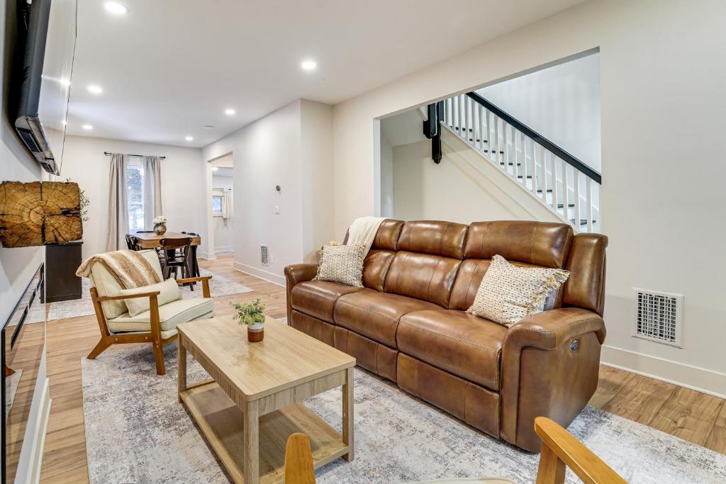 a living room with a brown leather couch and a table at Game Room and Backyard Modern Altoona Home! in Altoona