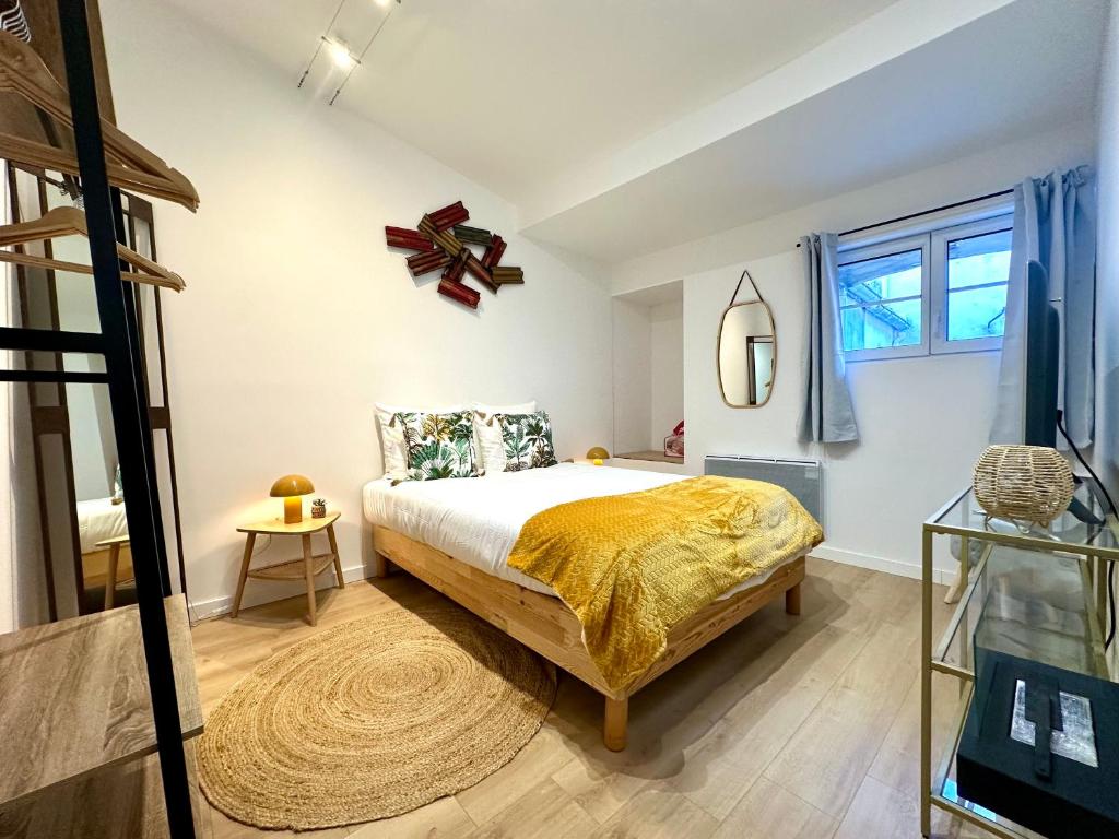 a bedroom with a bed with a yellow blanket at Charmant deux pièces en plein centre-ville de NARBONNE in Narbonne