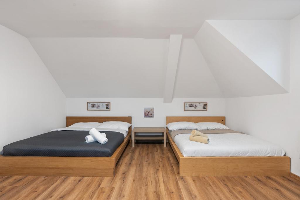 twee bedden in een kamer met witte muren en houten vloeren bij The Dante House Šeberov in Praag