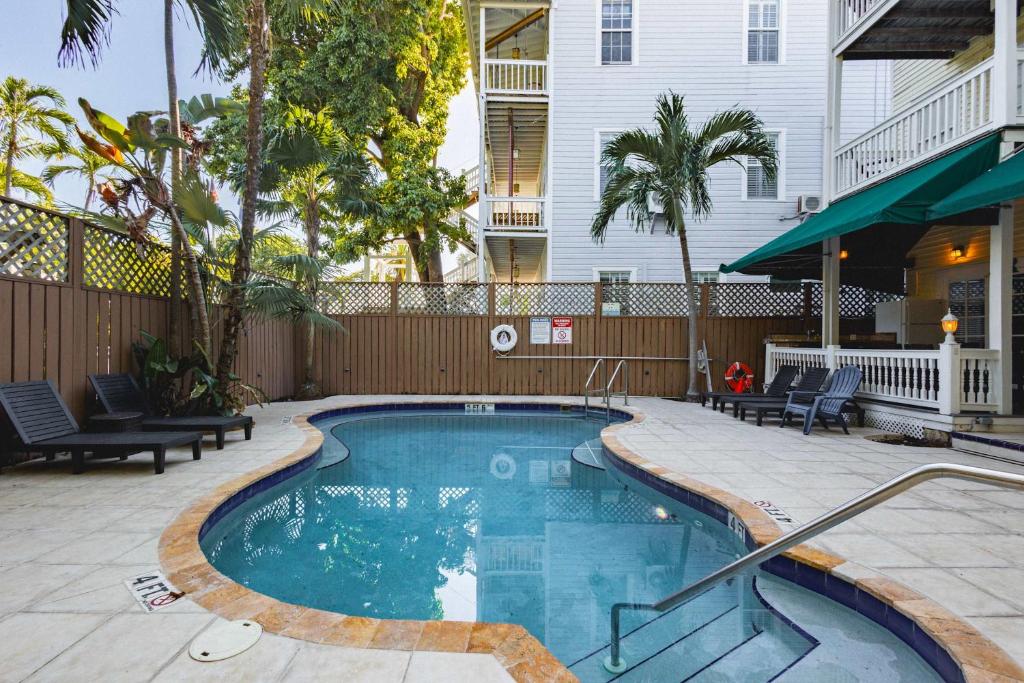 une piscine dans une cour avec des chaises et un bâtiment dans l'établissement Curry House - Room 9, à Key West