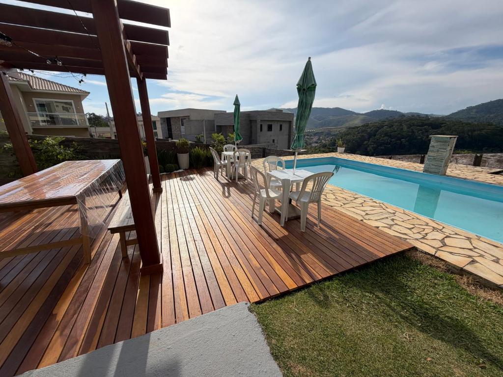 a wooden deck with a table and chairs next to a pool at Suite Requinte da Serra in Miguel Pereira