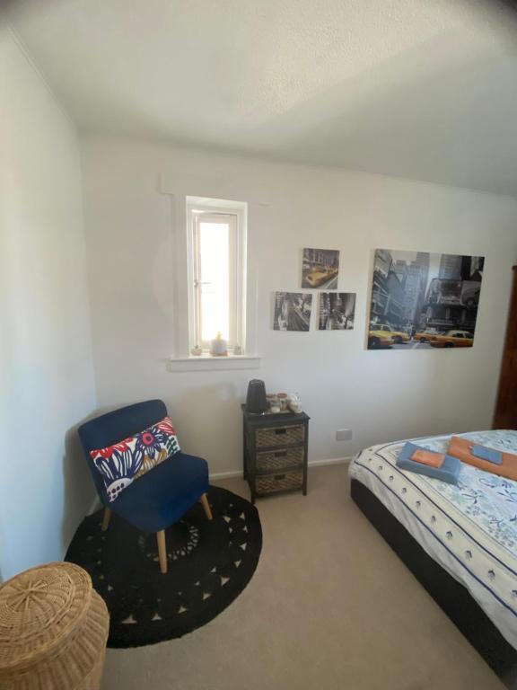 a bedroom with a bed and a blue chair at Mel house in Fife