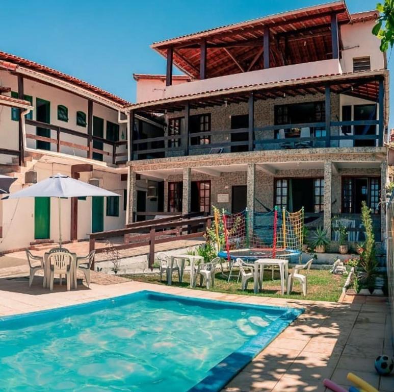 Un complejo con piscina y sillas y un edificio. en Pousada Alto Mar Saquarema, en Saquarema
