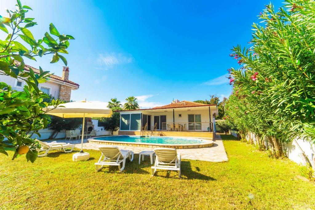 podwórko z basenem, krzesłami i domem w obiekcie Villa Sena w mieście Dalyan