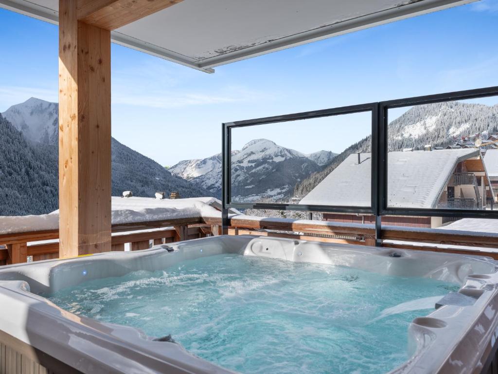 a hot tub on a balcony with a view of mountains at L'O Rouge - Apt A02 - BO Immobilier- remises sur les forfaits de skis Châtel ou Portes du soleil in Châtel