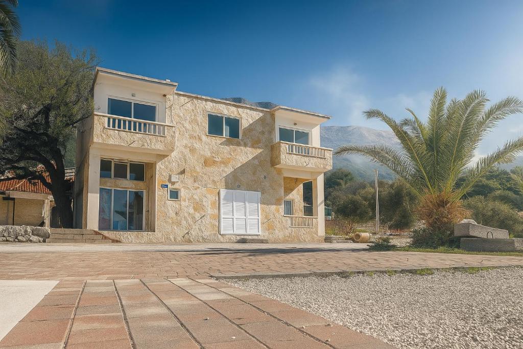 una grande casa in pietra con una palma di Apartmány Júlia a Živogošće (Svogoschia)