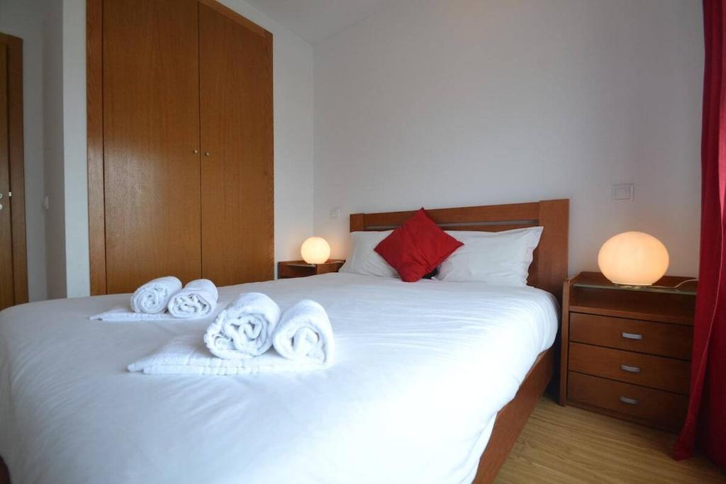 ein Schlafzimmer mit einem weißen Bett mit Handtüchern darauf in der Unterkunft 2-bedroom apartment with pool, 5-minute walk to the beach in São Martinho do Porto