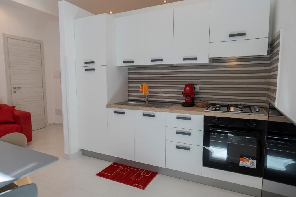 una cucina con mobili bianchi e un forno a piano cottura di Marusu Apartments a Terrasini