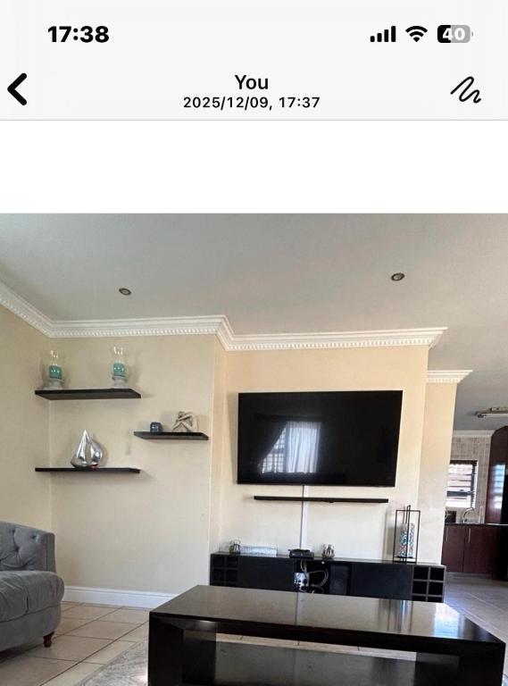 een woonkamer met een flatscreen-tv aan de muur bij Holiday Home in Cape Town