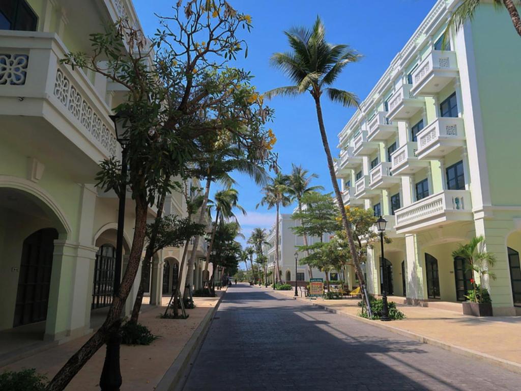 a street with palm trees in front of a building at HADU Hotel & Café Phu Quoc in Phú Quốc