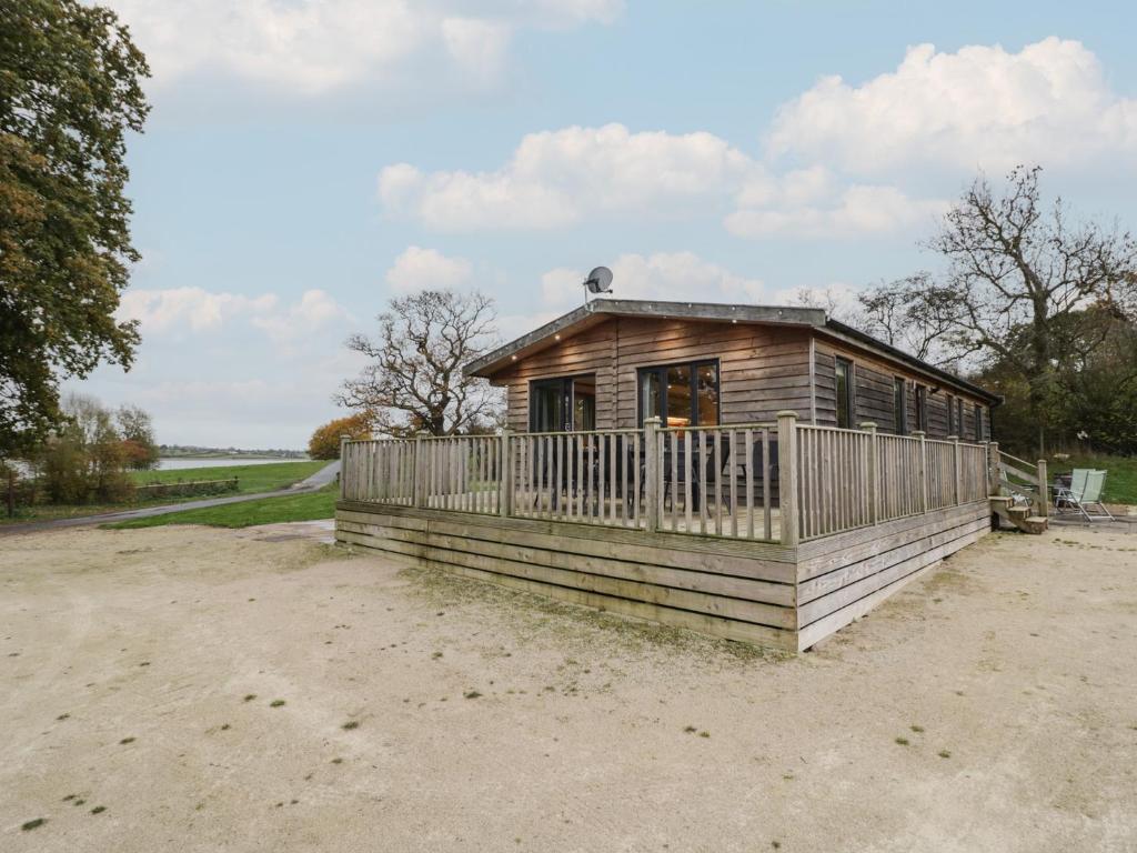 a small wooden house with a porch on a field at Oak Lodge in Rugeley