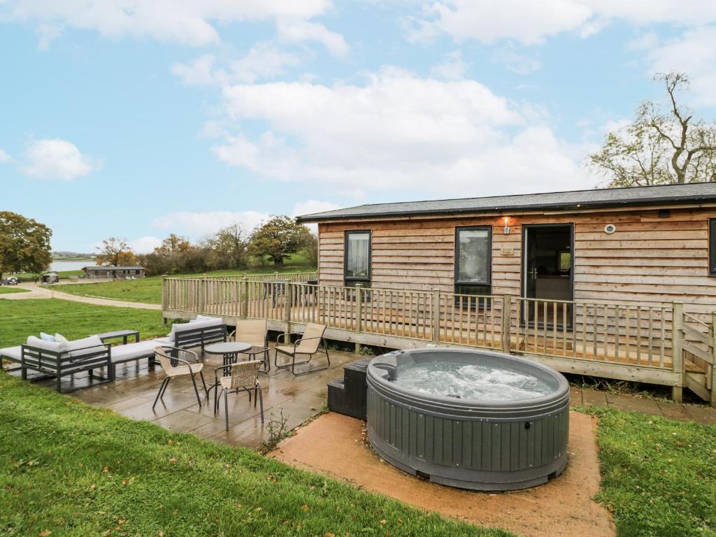 a deck with a hot tub and a table and chairs at Willow Lodge in Rugeley