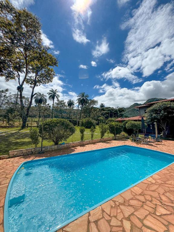a swimming pool with blue water in a yard at Pousada Mandalla in Serra do Cipo