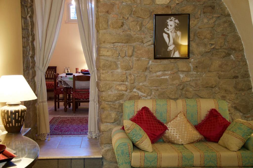 sala de estar con pared de piedra y sofá en Appartamento Antica Acropoli, en Centuripe