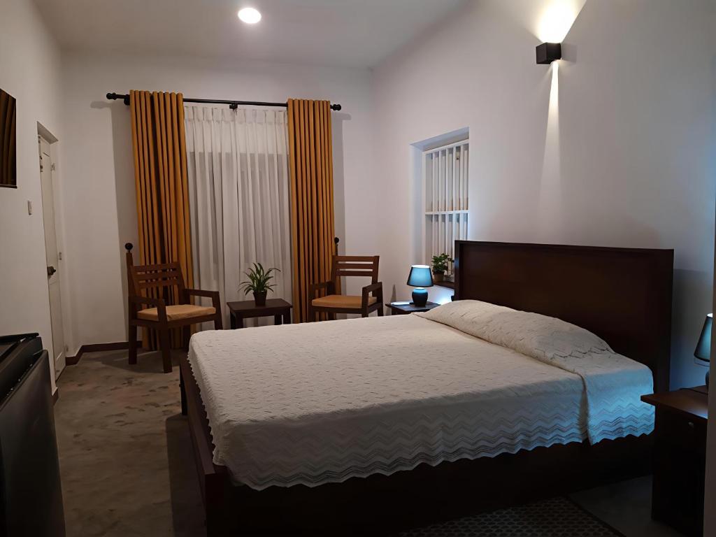 a bedroom with a bed and chairs in it at Coastal Residence in Hikkaduwa