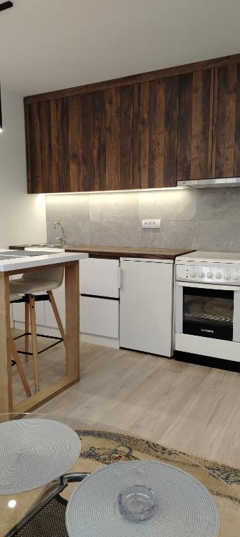 cocina con armarios blancos, mesa y fogones en Masa, en Arandjelovac