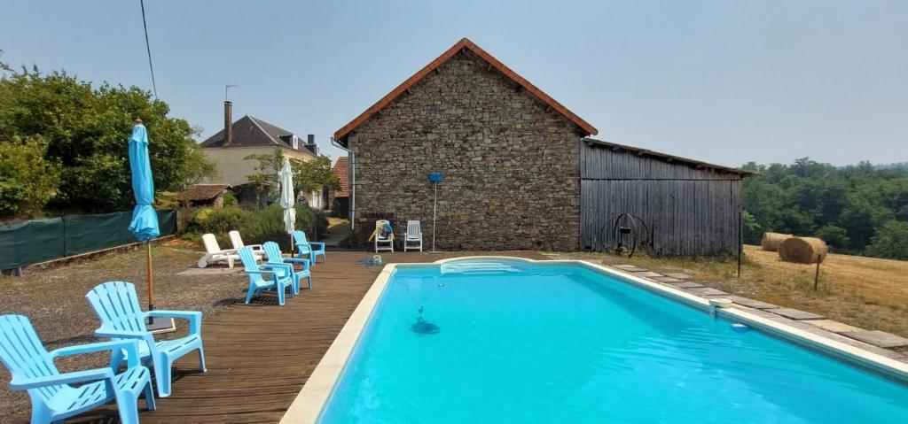 ein Pool mit blauen Stühlen und ein Gebäude in der Unterkunft Maison de Vacances Chez La Prade in Salagnac