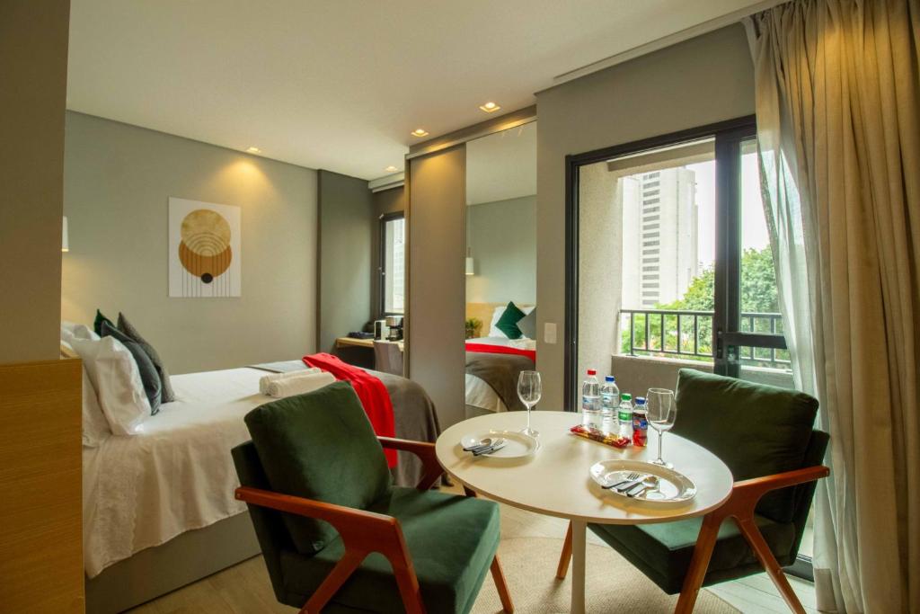 um quarto de hotel com uma cama, uma mesa e cadeiras em Novo e Aconchegante Caminhe ao Allianz Parque em São Paulo