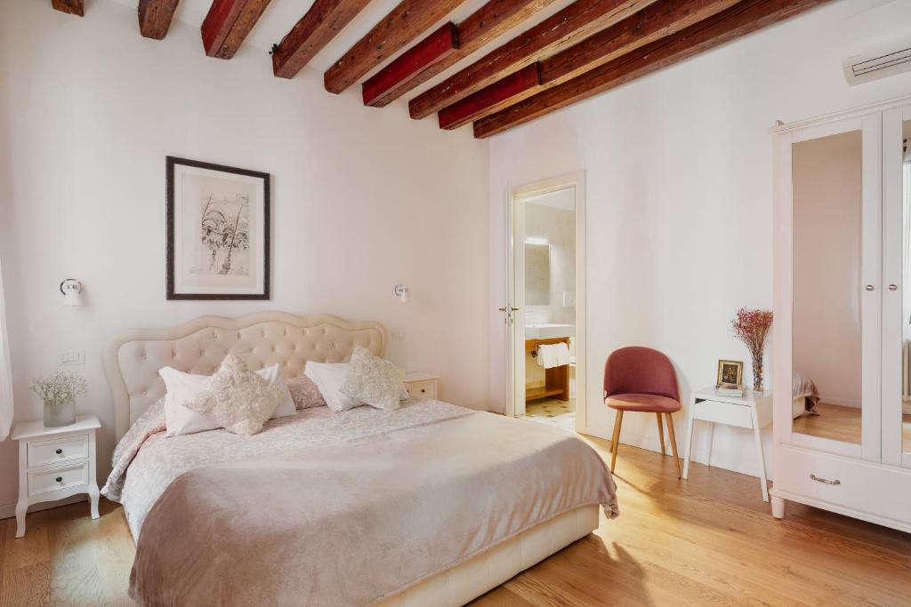 um quarto branco com uma cama grande e uma cadeira em Bianca Cappello House em Veneza