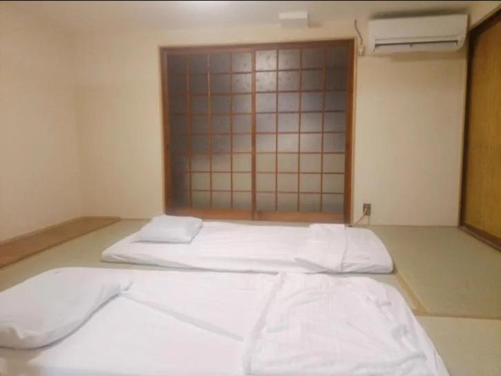 a bedroom with two white beds in a room at ふるさと in Wada