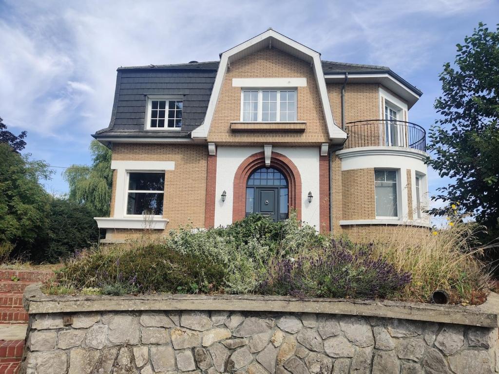 a house with a stone wall in front of it at Gite du bout là haut in Audincthum