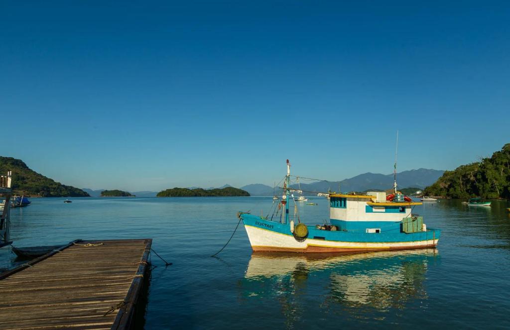 una barca è ormeggiata in acqua accanto a un molo di Canto Sereno Refúgio entre Praias e Ilhas a Parati