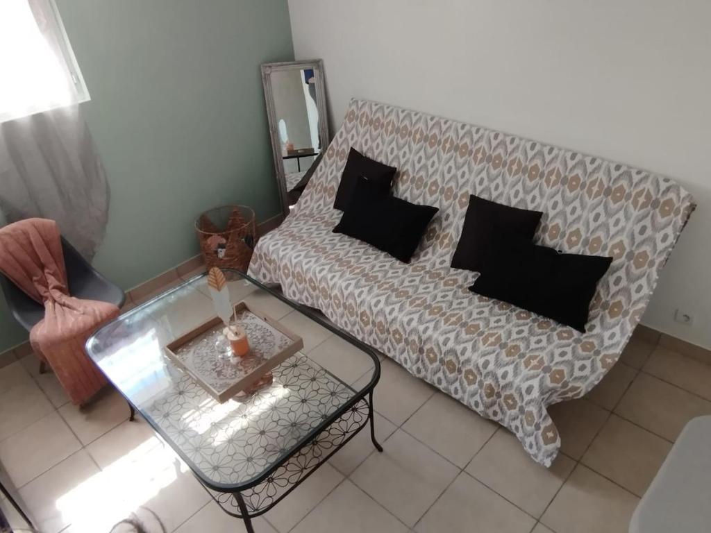 Studio cosy charmant في ميتري موري: غرفة معيشة مع أريكة وطاولة زجاجية