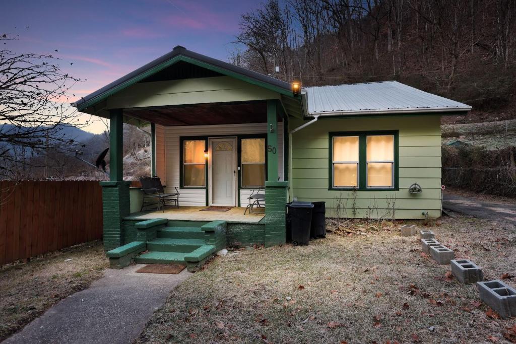 een klein groen tiny house met een veranda bij Cozy Matewan Trail Stay home in Delbarton