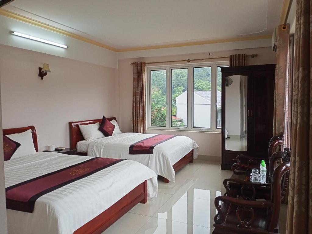 Una habitación de hotel con dos camas y una ventana. en Khách sạn Thành Loan 2, en Cao Bằng