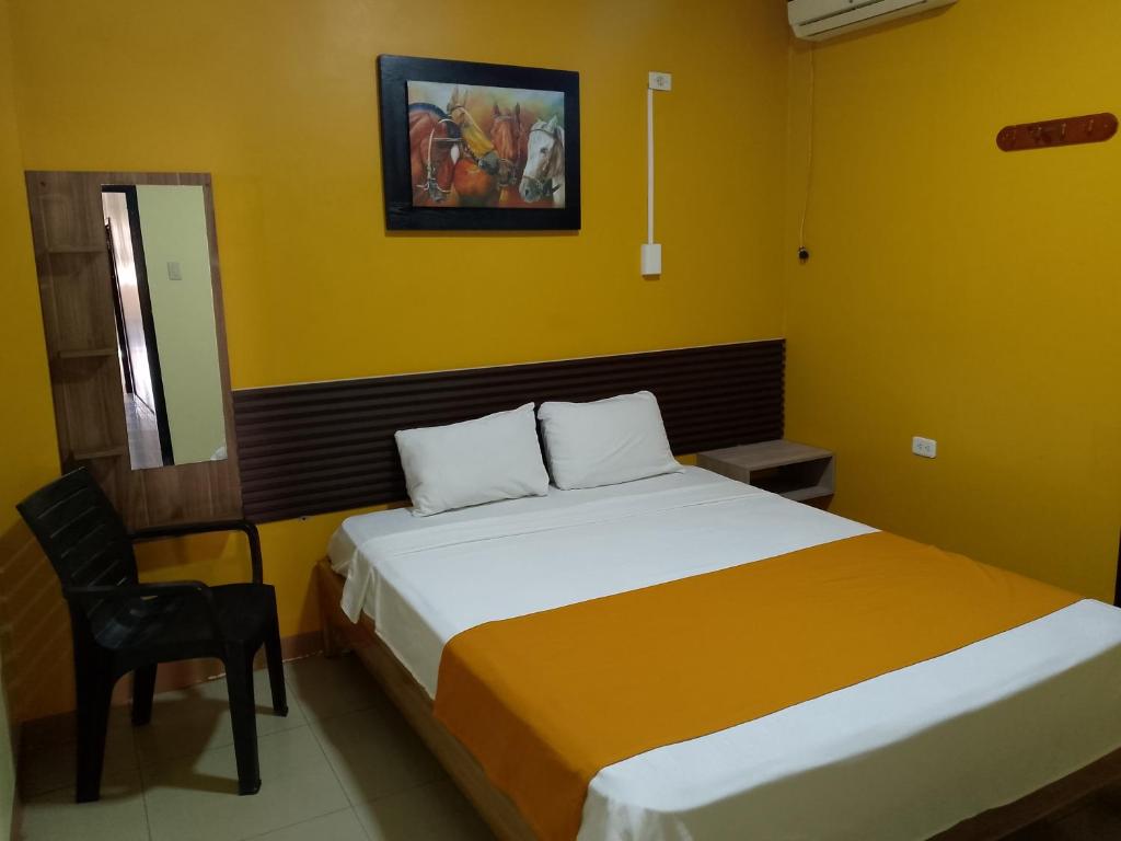 Un dormitorio con una cama y una silla dentro. en Hotel Lanus, en Portoviejo