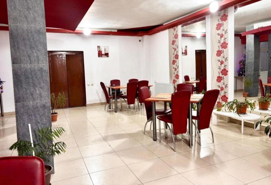 a dining room with tables and red chairs at Pensiunea Casa Raul in Cluj-Napoca