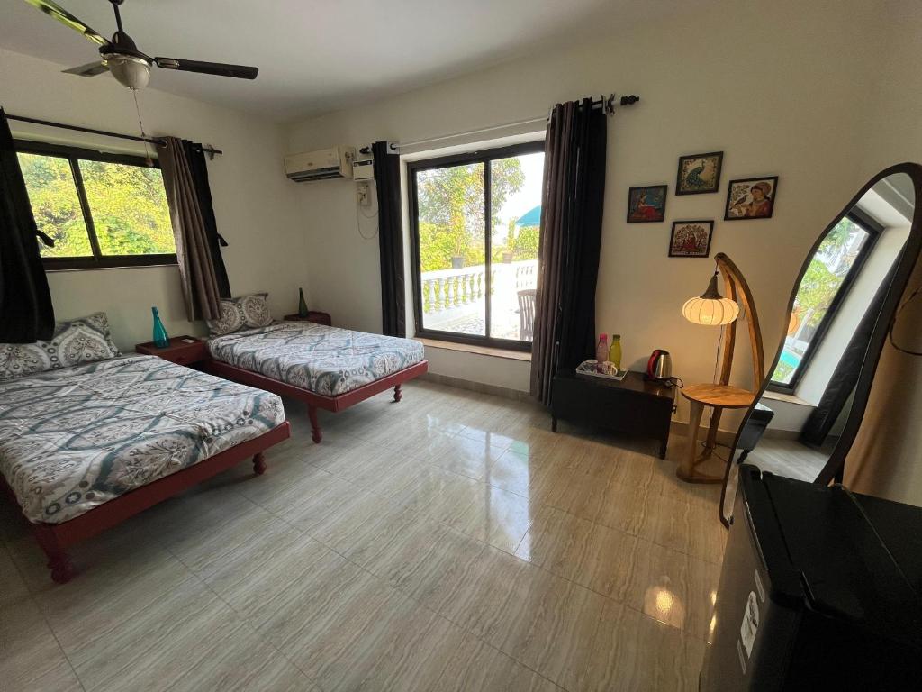 Indigo Orchid Homestay - A spacious, serene villa with terrace and farm view في Saligao: غرفة معيشة بها سريرين ونافذة