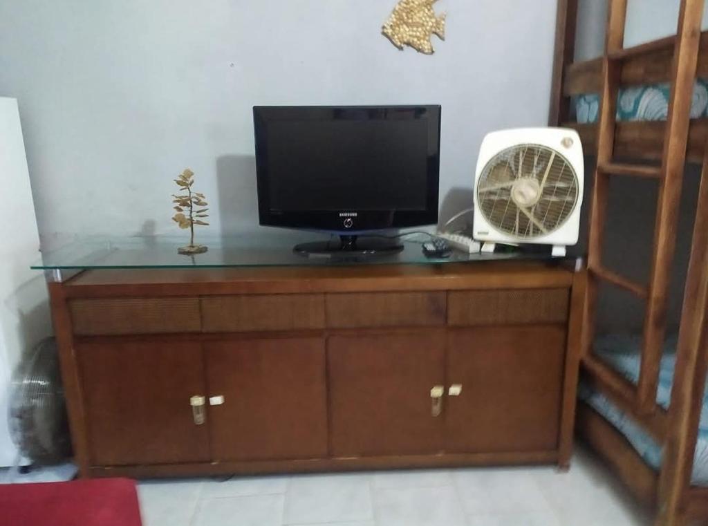 a television and a fan sitting on a dresser at Casa Temporada Caraguatatuba in Caraguatatuba