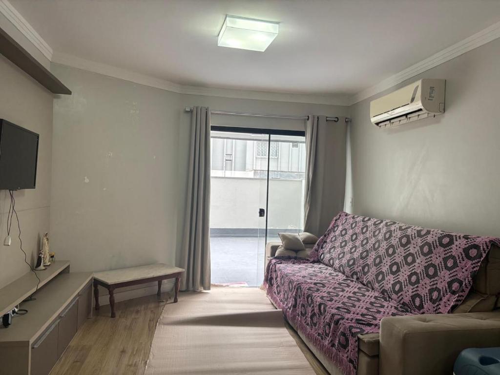ein Wohnzimmer mit Sofa und Glasschiebetür in der Unterkunft Ap Pertinho do Mar! in Balneário Camboriú