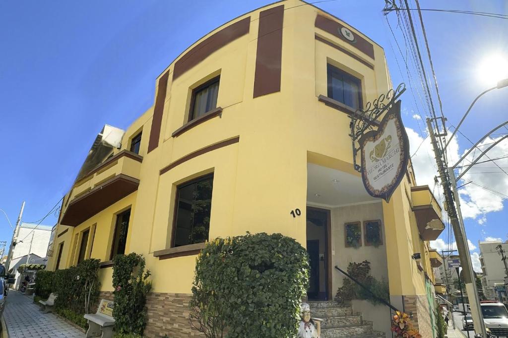 a yellow building with a clock on the side of it at Hotel Vitoria Marchi in Serra Negra