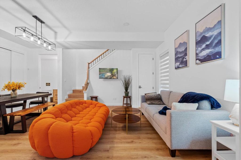 an orange ottoman in a living room with a couch at Luxurious Large 3 Bedroom Loft Saskatchewan Drive in Edmonton