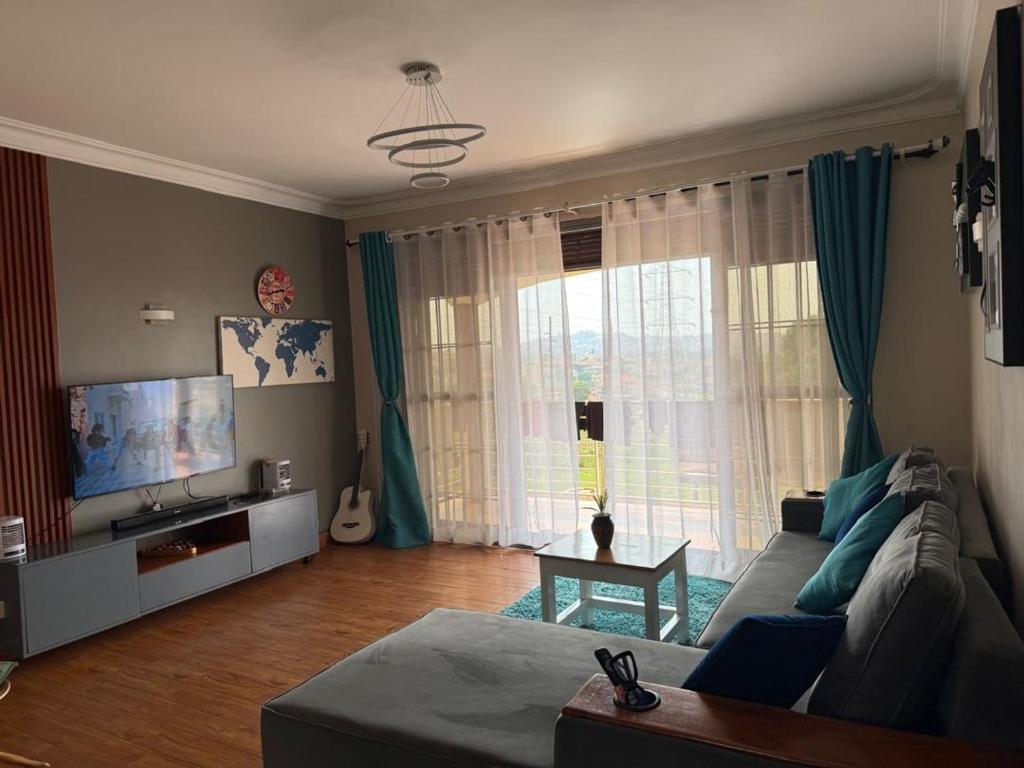 a living room with a couch and a large window at Ariette Homes in Buwate