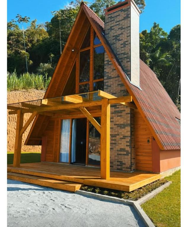 a house with a pitched roof and a deck at Recanto do Tabuleiro chalé com hidro, lareira, churrasqueira e cozinha perto de floripa in Aguas Mornas