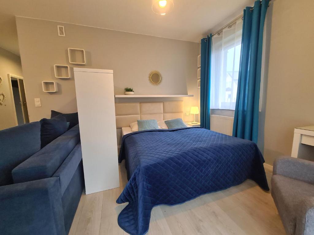 a bedroom with a blue bed and a couch at APARTAMENTY "LA VILLA" SUPERIOR III na parterze z prywatnym ogrodem, tarasem, parkingiem, blisko centrum, spokojna okolica in Kudowa-Zdrój