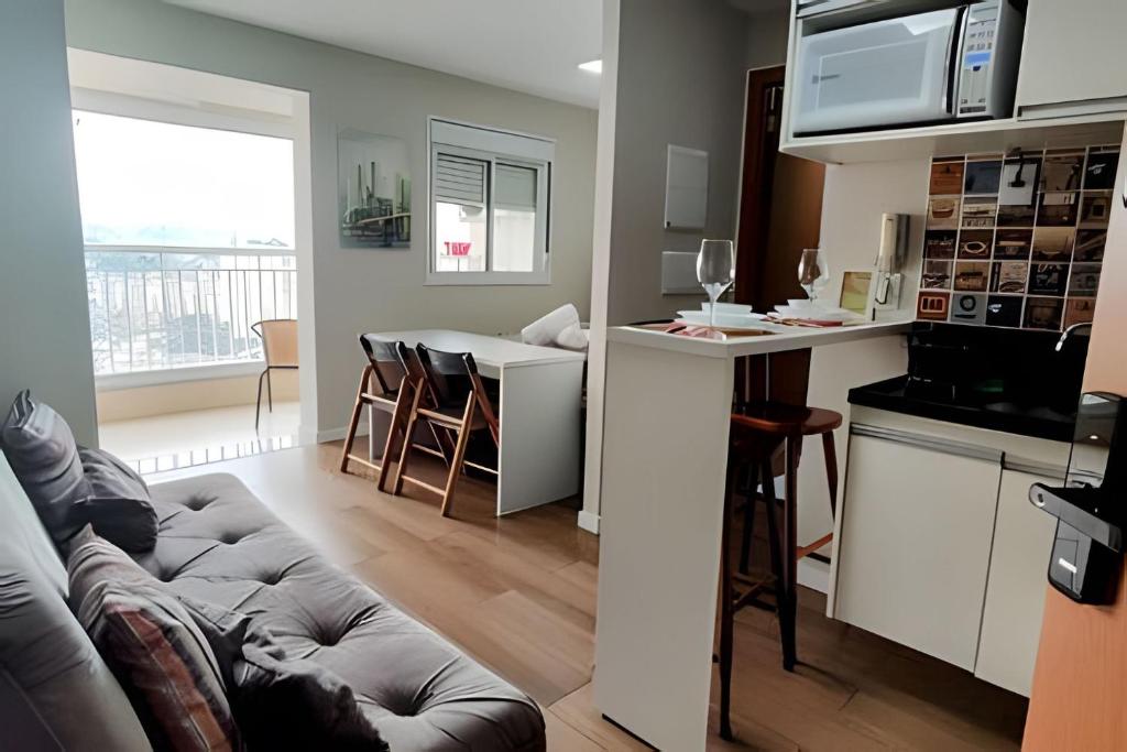 a living room with a couch and a kitchen at Aeroporto GRU e Shopping Maia, com Ar Condicionado in Guarulhos