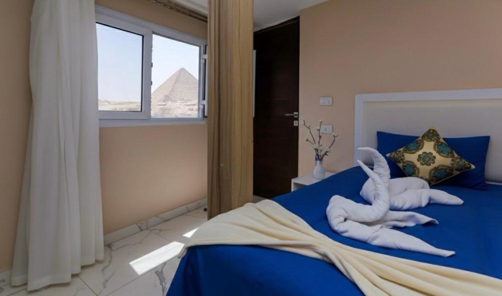 Un dormitorio con una cama azul con un animal de toallas. en rizkyan pyramids giza view INN, en El Cairo