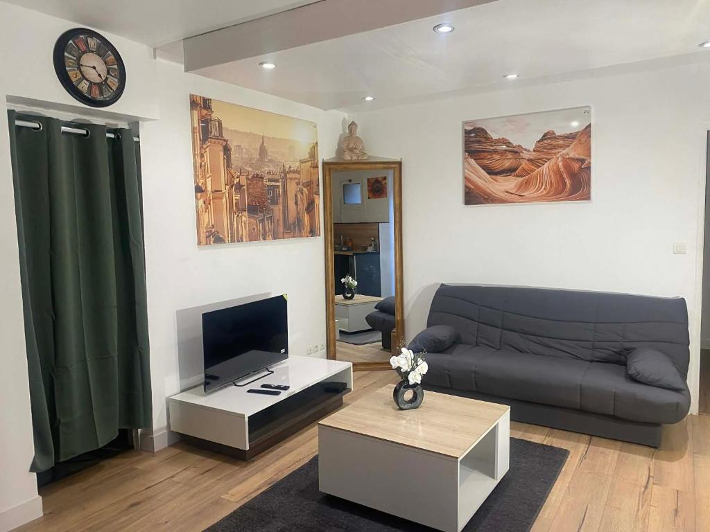 a living room with a couch and a clock on the wall at T2 COCOON Centre ville in Marmande