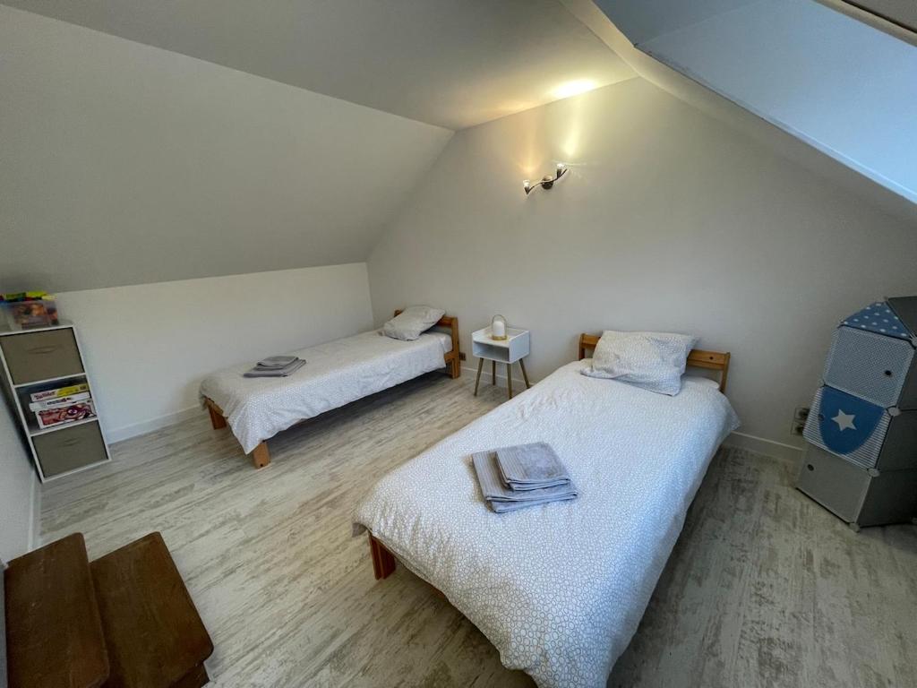 Una pequeña habitación con dos camas y una mesa. en La petite maison des bleuets, en Romorantin-Lanthenay